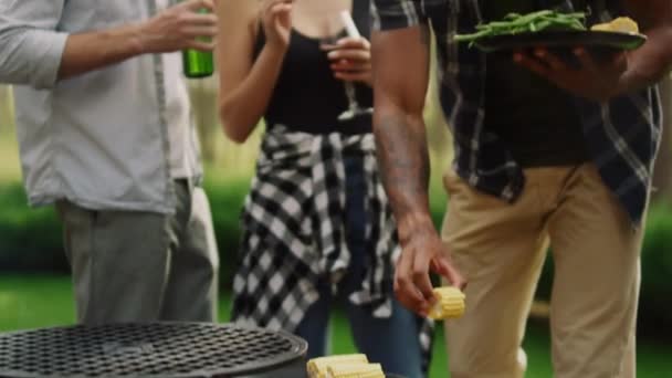 Focused man chef preparing bbq vegetables outside. Man putting corn on grill — Stock Video