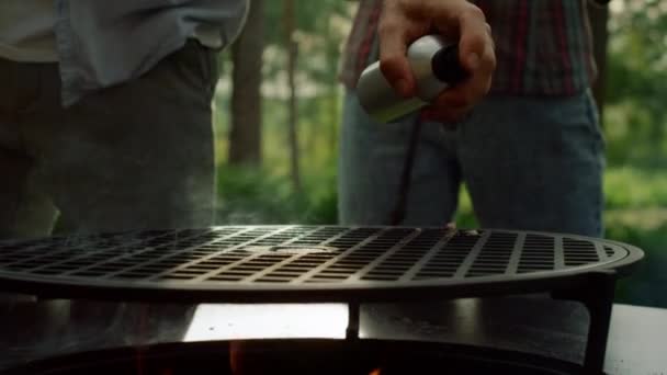 Male person getting ready for bbq party outside. Man chef spraying oil on grille — Stock Video