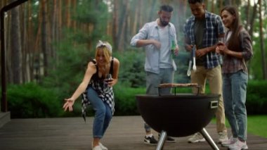 Dışarıda BBC ızgarasının yanında dinlenen adamlar var. Gülümseyen kadın arka bahçede köpek çağırıyor..