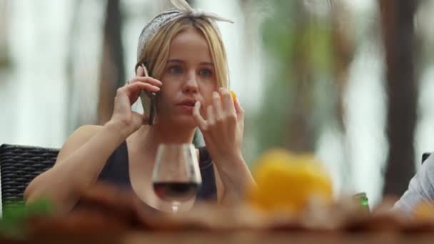 Skupiona dziewczyna mówiąca przez telefon komórkowy na zewnątrz. Kobieta je pomidory wiśniowe na zewnątrz — Wideo stockowe