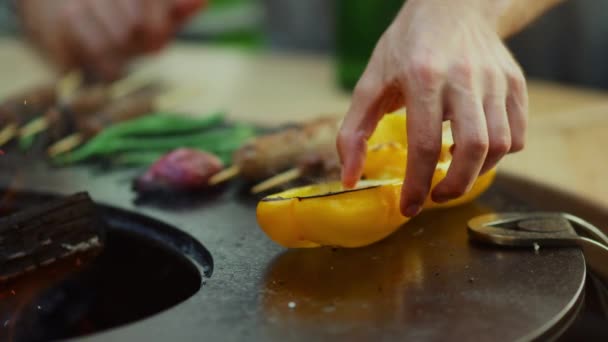 Un tipo desconocido cocinando comida en la parrilla de barbacoa afuera. Pimienta amarilla en rejilla — Vídeos de Stock