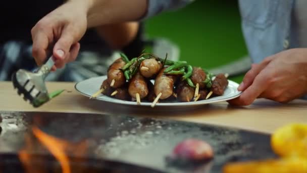 Um tipo desconhecido a pôr vegetais no prato lá fora. Homem chef usando fórceps ao ar livre — Vídeo de Stock