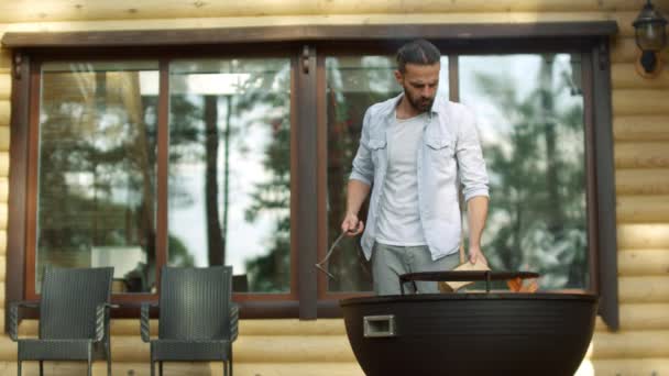 Skupiony facet używający pokera na świeżym powietrzu. człowiek szef kuchni gotowania żywności na grill w pobliżu domu. — Wideo stockowe