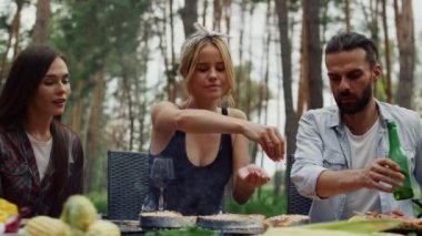 Gülümseyen kız dışarıda yemek yapmayı bitiriyor. Kadın balığa baharat ekliyor.