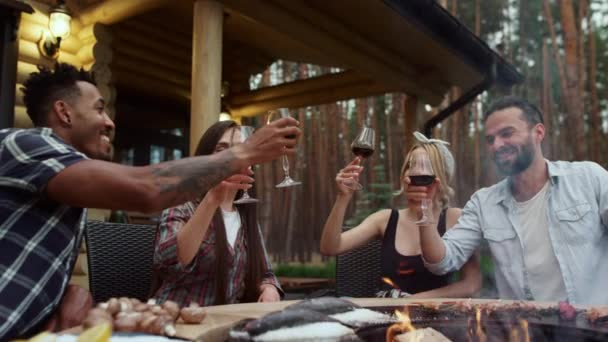 Amigos alegres batendo óculos na festa bbq fora. Rapazes a beber vinho tinto — Vídeo de Stock