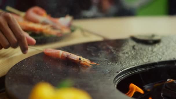 Amigos preparando comida para a festa do churrasco lá fora. Caras colocando camarão na grelha — Vídeo de Stock