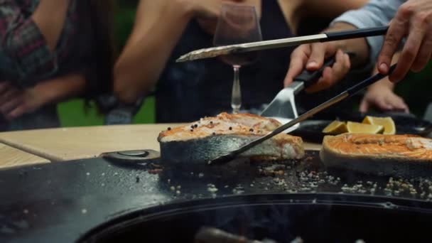 Homem chef transformando fatia de peixe na churrasqueira lá fora. Guy cozinhar com ferramentas de cozinha — Vídeo de Stock