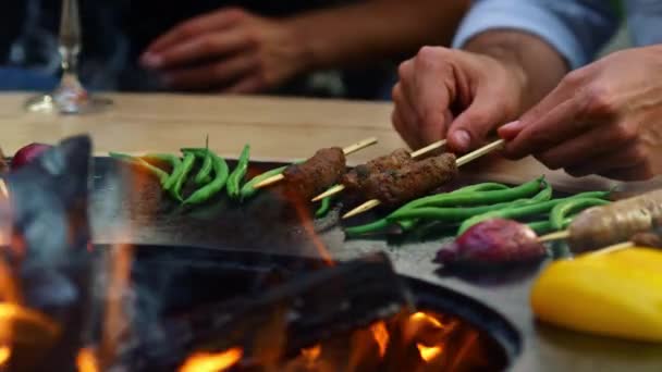 Un hombre irreconocible haciendo kebab afuera. Chico desconocido cocinando carne en palos — Vídeos de Stock