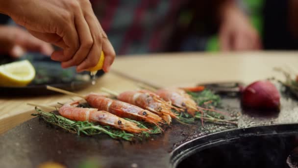 Okänd person som klämmer citron på räkor utomhus. Ritar bruna med örter — Stockvideo