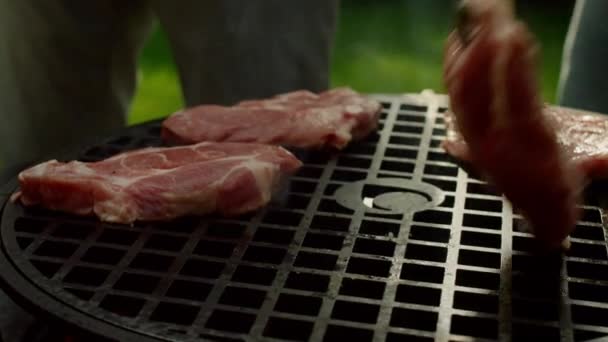 Man handen zetten vlees plakjes op rooster buiten. Chef bereidt vlees in het bos — Stockvideo