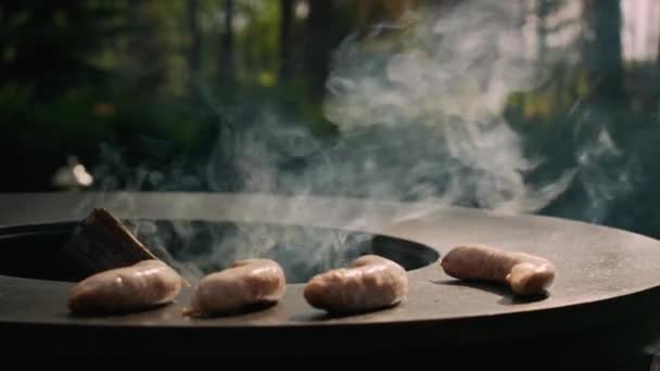 Onherkende man zet worsten op bbq grill buiten. Kok koken worstjes — Stockvideo