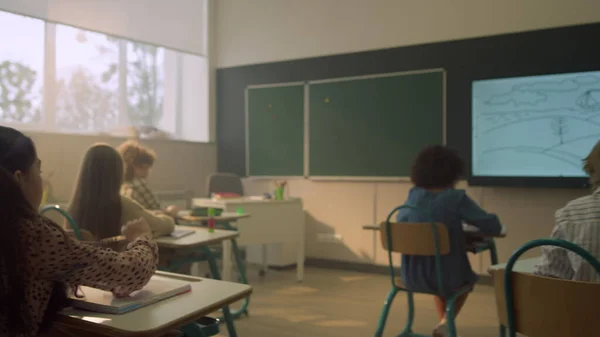 Colegiales sentados en escritorios en el aula durante la lección en la escuela primaria —  Fotos de Stock