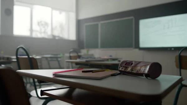 Cuaderno, bolígrafos y estuche de lápices en el escritorio en el aula. Material escolar en la mesa —  Fotos de Stock