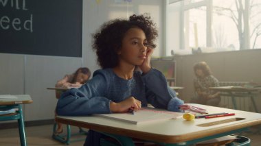 Sınıfta okul masasında oturan düşünceli bir öğrenci. Bilim öğrenen kız öğrenci.