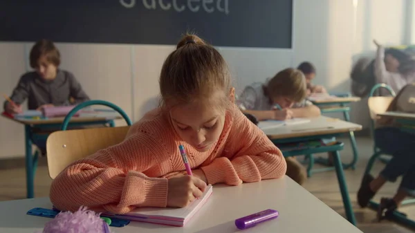 Schoolmeisje maakt aantekeningen in het notitieboekje. Slimme student schrijven in het oefenboek — Stockfoto