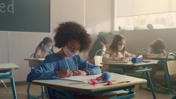 Koronavirüs salgını sırasında sınıfta çalışan maskeli çocuklar.