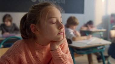 Sınıfta masa başında oturan hayalperest çocuk. Pencereye bakan düşünceli liseli kız