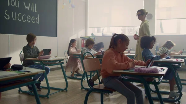 Joven maestra de escuela hablando con los alumnos. Profesor explicando lección a los estudiantes —  Fotos de Stock