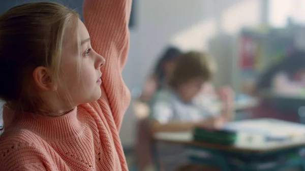 Une fille assise au bureau en classe. Étudiant intelligent levant la main pour poser la question — Photo