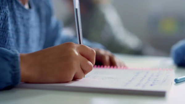 Colegiala mano haciendo trabajo de clase en el escritorio. Chica escribiendo en cuaderno — Foto de Stock