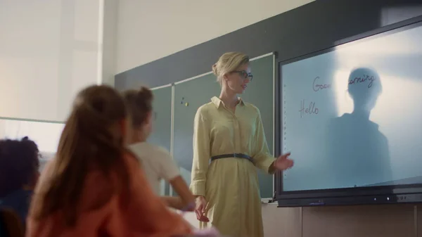 Jong schooljuf en schoolmeisje staan op smart board in de klas — Stockfoto