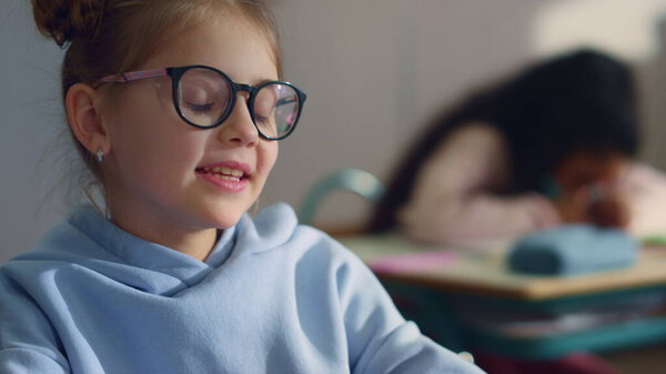 Girl answering for question at lesson in school. Student talking in classroom