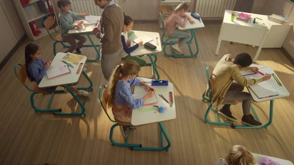 Estudantes a escrever em cadernos. Professora de escola procurando crianças fazendo teste — Fotografia de Stock