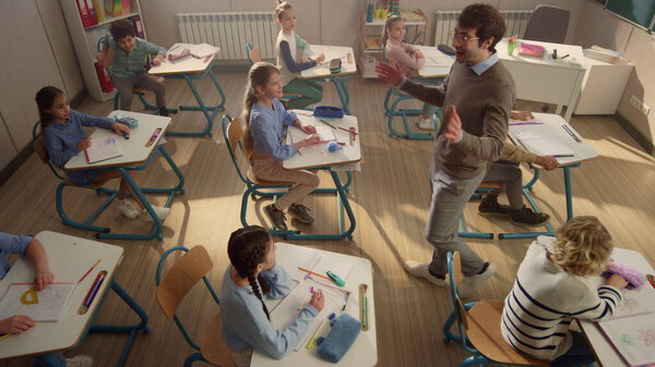 Schoolteacher talking with pupils. Students running from classroom for holidays