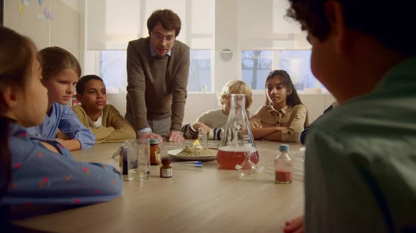 Kinder, die am Tisch Chemie studieren. Lehrer macht Pharaonschlangen-Experiment — Stockfoto