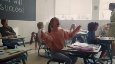 Çocuklar sınıfta eğleniyor. Karma ırk öğrencileri kağıt uçaklarla oynuyor.