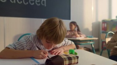 Sınıfta öğrenme odaklı çocuk. Akıllı çocuk derste deftere yazıyor.