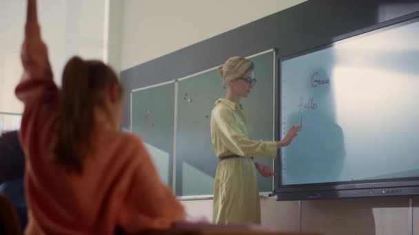 Profesor escribiendo en pizarra digital interactiva. Estudiantes levantando manos — Vídeo de stock