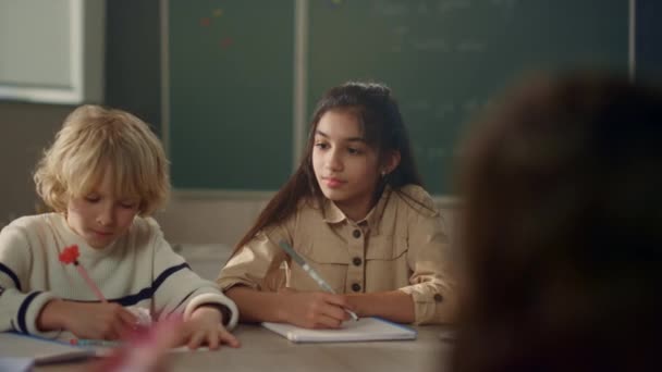 Studenti se učí u kulatého stolu ve škole. Zorničky zapisující text do sešitů — Stock video