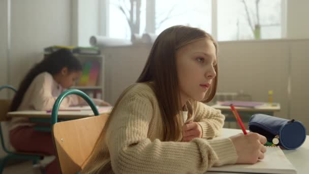 Chica diligente escribiendo en cuaderno durante la lección en la escuela. Estudiante tomando notas — Vídeos de Stock