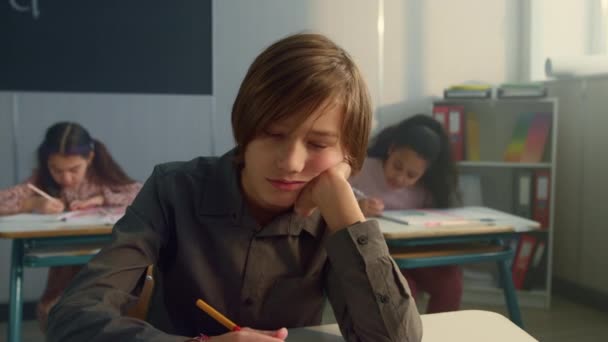 Müder Schüler sitzt im Klassenzimmer. Fröhlicher Junge langweilt sich im Unterricht — Stockvideo