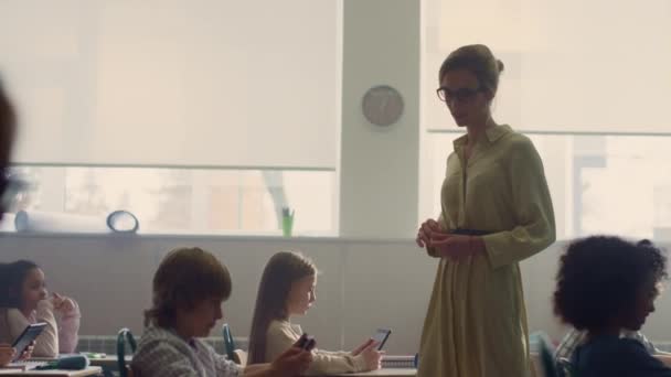 Profesor caminando entre escritorios. Alumnos que buscan internet en tabletas digitales — Vídeo de stock