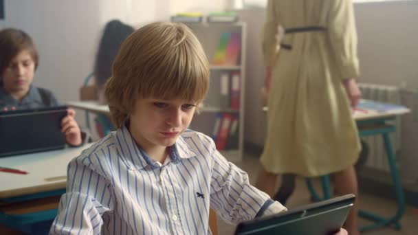 Мальчик смотрит на экран цифрового планшета во время урока. Обучение с помощью блокнота — стоковое видео