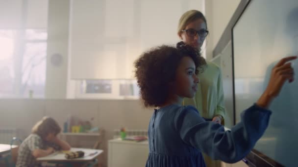 Schoolmeisje schrijven op interactieve digitale whiteboard. Afro meisje maken taak — Stockvideo