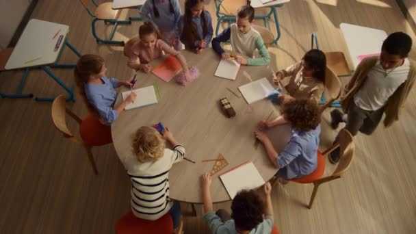 Des enfants assis à table ronde à l'école. Divers étudiants se préparent pour la leçon — Video