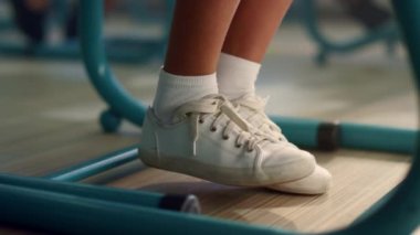 Kapanış kızı bacaklarını oynatıyor. Sınıfta okul masasının altında kız öğrenci ayakları.