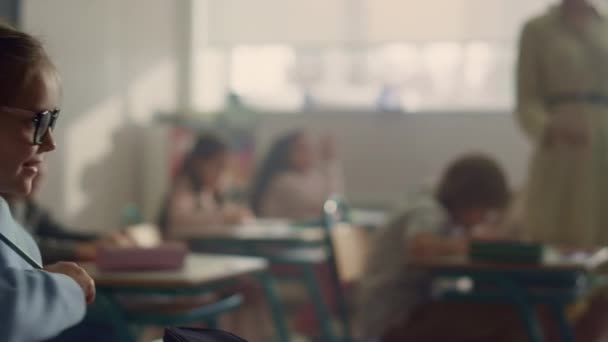 Děti sedí za stolem ve škole. Učitel kontroluje domácí práci ve třídě — Stock video