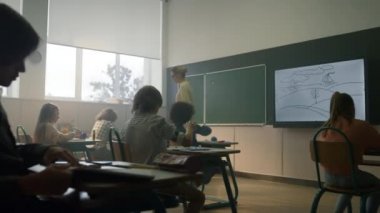 Öğretmen öğrencilere bilgi veriyor. Okul öğretmenini dinleyen çocuklar