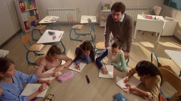 Étudiants assis à la table ronde en classe. Enseignant expliquant la tâche de leçon — Video