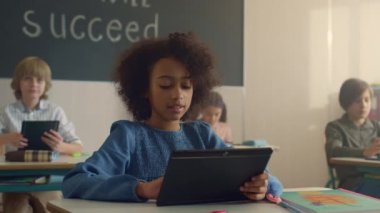 Sınıfta dijital tablet tutan bir öğrenci. Tablet bilgisayar kullanan kız öğrenci 