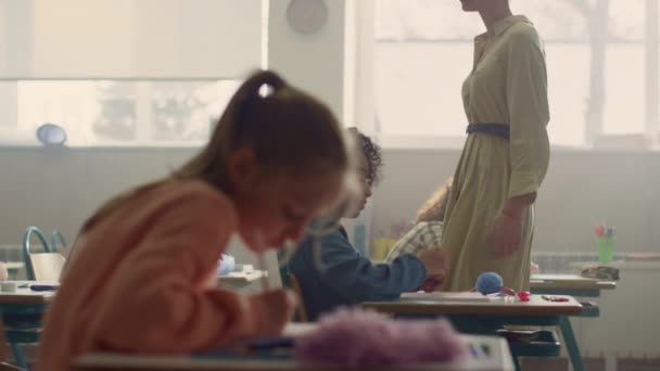 Les enfants font du travail de classe aux bureaux. Enseignant expliquant la leçon aux élèves — Video