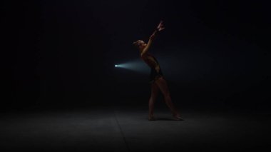 Karanlık uzayda takla atan esnek bir kız. Sporcu kadın takla atıyor.