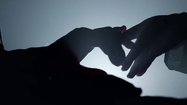 A sziluett pár keze sötétben tapogatózik. Férfi nő karok megérintik egymást — Stock Fotó