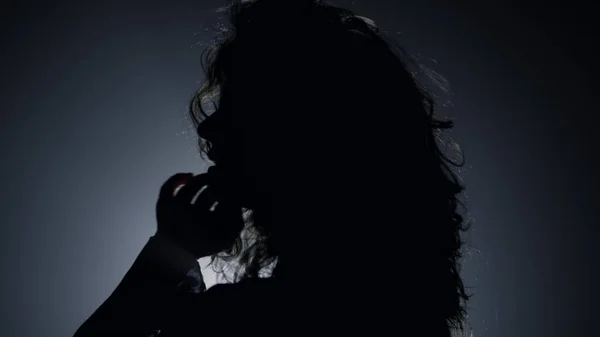 轮廓漂亮的女人在黑暗中摆姿势拍照.爱抚头发的女人 — 图库照片