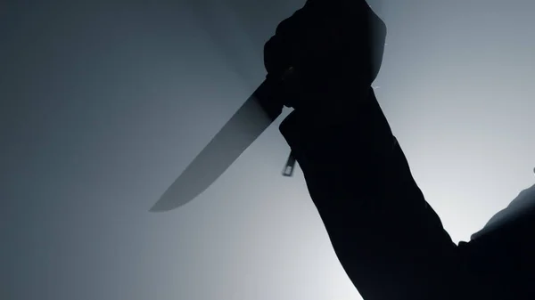 Silhouette mano criminale che attacca con un coltello nell'oscurità. Arma in mano — Foto Stock