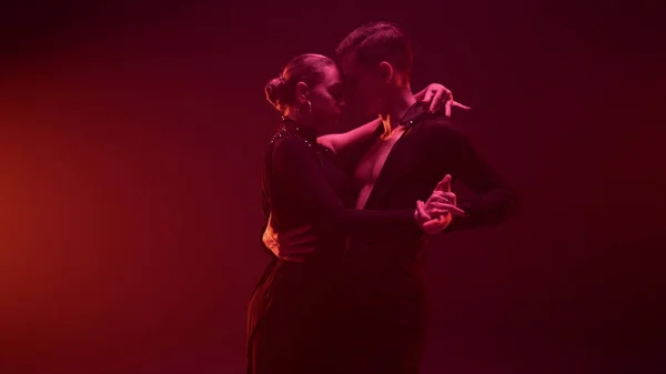 Élégants danseurs posant caméra studio sombre. Élégant couple de danse tenant la main. — Photo